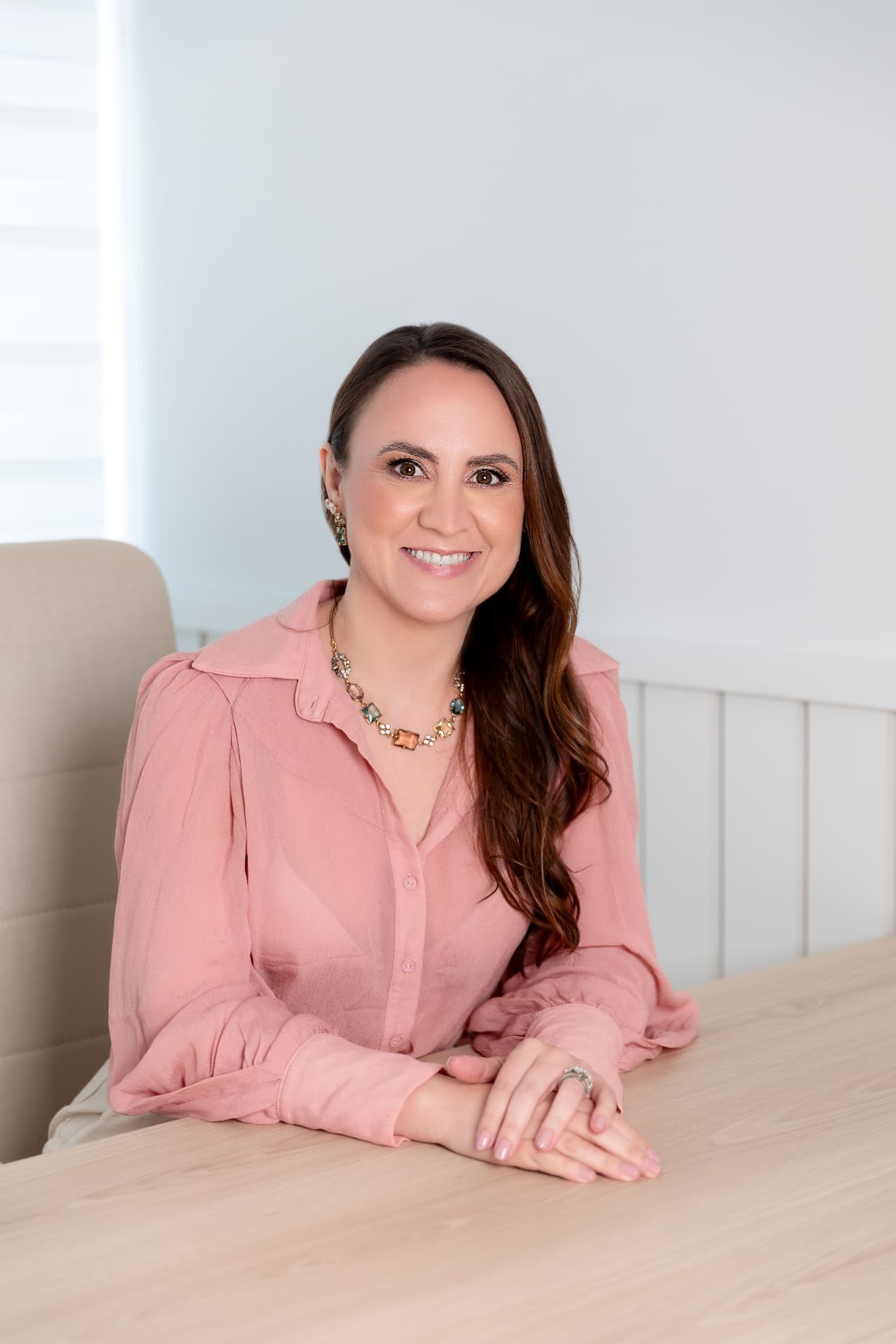 Milene Peruzzo, psicóloga CRP-08/18803, sentada à mesa do consultório